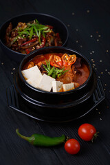 Korean food. Traditional Kimchi soup. on a black wooden background.
