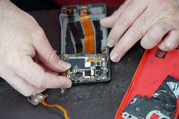 technician repairing mobile phone with his hands, disassembling different types of parts of the device, from the plate to the camera area