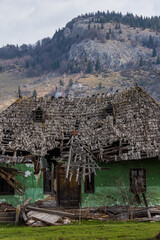 An abandoned uninhabited rural house with a collapsed roof, front view. An old abandoned traditional wooden building in Romania village, falling apart from the effects of atmospheric precipitation.