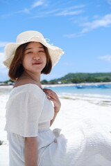 a beautiful girl wearing a beach dress is enjoying her summer vacation on Mandalika beach with sunny weather and blue skies