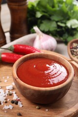 Delicious ketchup in bowl and spices on table, closeup. Tomato sauce