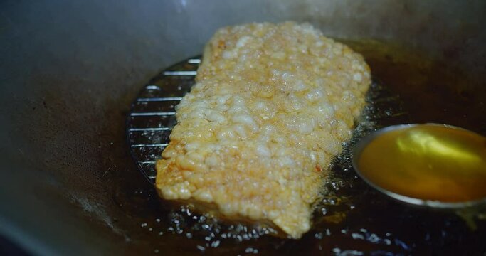 Cooking Crispy golden-brown pork skin in hot oil, sizzling in a deep frying pan, capturing the essence of delicious thai cuisine
