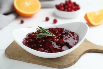 Fresh cranberry sauce and rosemary in bowl on white table, closeup