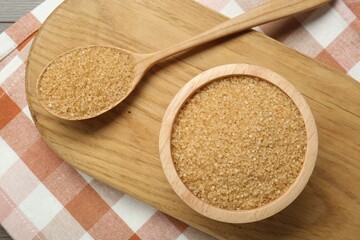 Brown sugar in bowl and spoon on table, top view