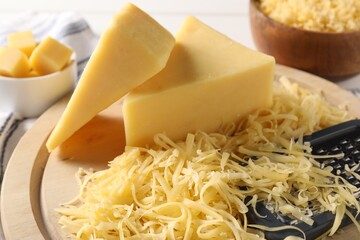 Grated and whole pieces of cheese on board, closeup