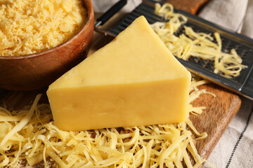 Grated and whole piece of cheese on table, closeup