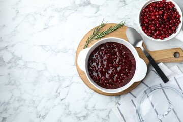 Fresh cranberry sauce in bowl served on white marble table, flat lay. Space for text
