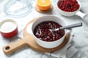 Fresh cranberry sauce in bowl served on white marble table, closeup