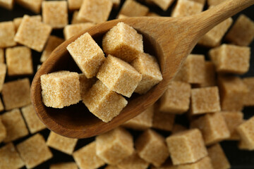 Spoon with brown sugar cubes over table, top view