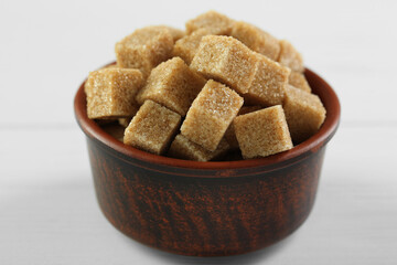 Brown sugar cubes on white table, closeup