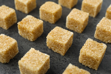 Brown sugar cubes on grey table, closeup