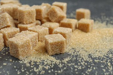 Brown sugar cubes on grey table, closeup