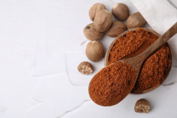 Nutmeg powder and seeds on white table, flat lay. Space for text