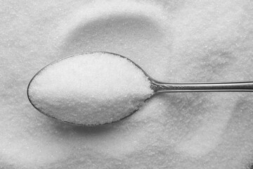 Metal spoon on granulated sugar, top view
