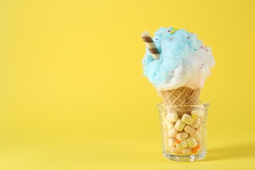 Sweet cotton candy in waffle cone on yellow background. Space for text