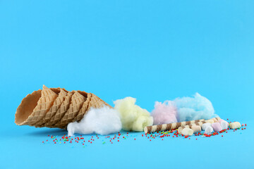 Sweet cotton candies, waffle cones, wafer sticks and marshmallows on light blue background