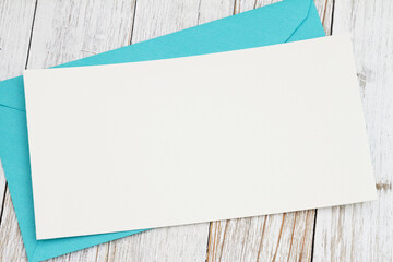 Blank greeting card with blue envelope on wood