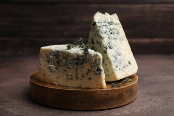 Tasty blue cheese with thyme on brown table