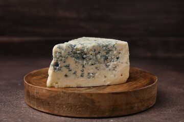 Piece of tasty blue cheese on brown table