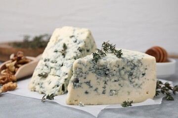 Tasty blue cheese with thyme on grey table, closeup