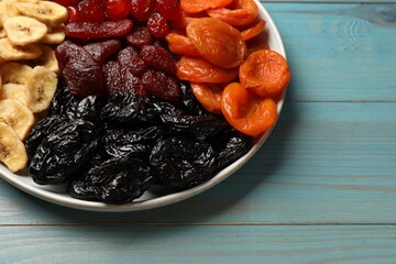 Delicious dried fruits on light blue wooden table, closeup. Space for text