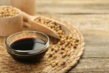 Soy sauce in bowl and beans on wooden table. Space for text