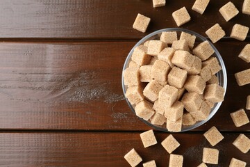 Brown sugar cubes on wooden table, flat lay. Space for text