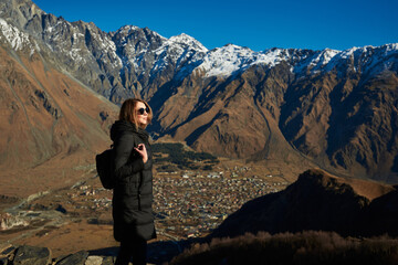 A beautiful tourist exploring the majestic brown mountains with snowy white tops.