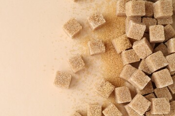 Brown sugar cubes on beige background, top view. Space for text