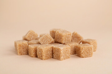 Pile of brown sugar cubes on beige background