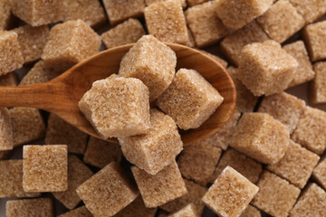 Wooden spoon on brown sugar cubes, above view