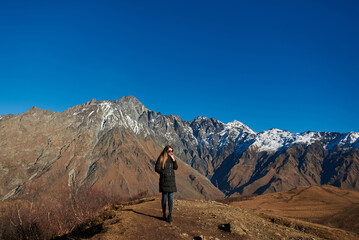 An attractive wanderer captivated by the splendor of the majestic brown mountains with snowy peaks.