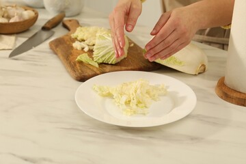 Obraz na płótnie Canvas Woman with cut Chinese cabbage at white kitchen table, closeup