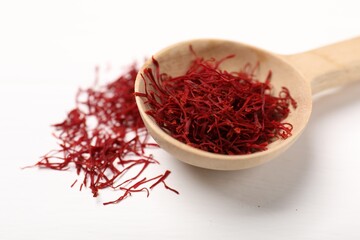 Aromatic saffron and spoon on white table, closeup