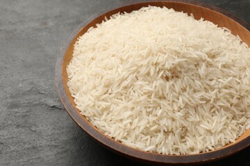 Fototapeta na wymiar Raw basmati rice in bowl on black table, closeup