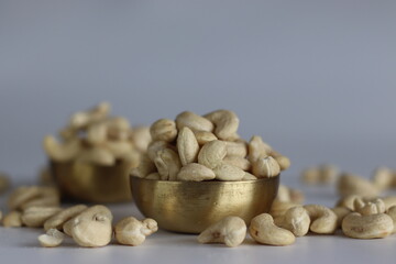 A heap of golden roasted cashews in a brass bowl.