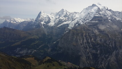 스위스 인터라켄의 융프라우 전망대에서 바라본 만년설에 휩싸인 설산의 풍경과 그 산 봉우리에 걸쳐진 풍성한 구름, 그리고 융프라우에서 개장한 눈썰매장을 위에서 내려다 본 장면, 설산의 봉우리에 걸친 높고 푸른 하늘과 하얀 뭉게구름 풍경입니다.  