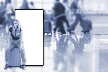 Young smiling woman is sitting on a suitcase in an airport terminal. Blurred figures of walking passengers are in the background. Travel concept.