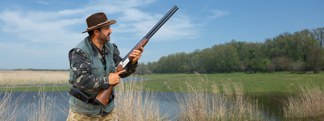 Hunter man in camouflage with a gun during the hunt in search of wild birds or game.