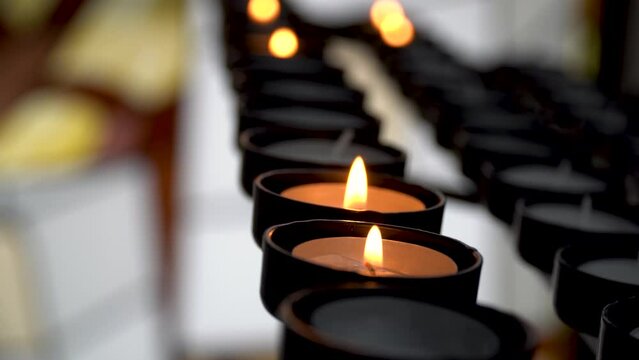 Slow motion, closeup to a group of candles for prayers