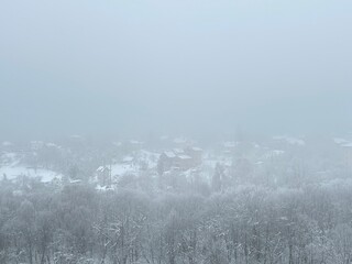 Panoramic view from above of a cottage settlement and forest in the mountains on a foggy winter...