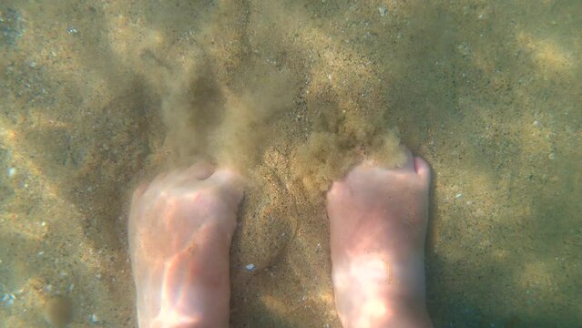 View of a woman's feet digging her toes into the sand under the water. Burying toes in sand under the surface of the water. Rest relaxation recreation relax