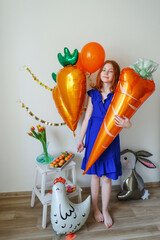 girl hug balloons of carrots and a cockerel is preparing to celebrate Easter