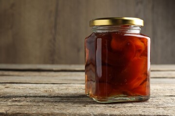 Tasty homemade quince jam in jar on wooden table, closeup. Space for text