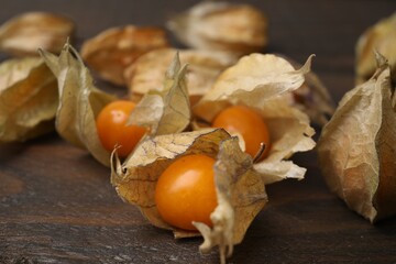 Ripe physalis fruits with calyxes on wooden table, closeup