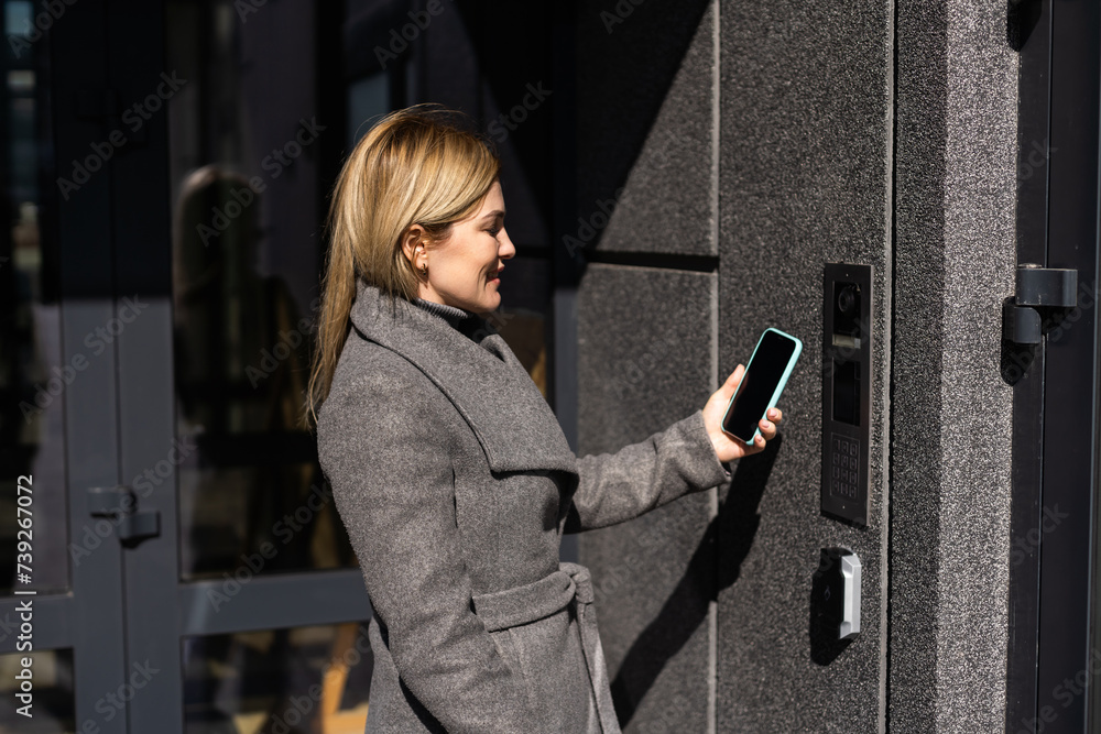 Poster woman locking smartlock on the entrance door using a smart phone. concept of using smart electronic 