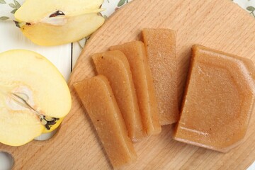 Tasty sweet quince paste and fresh fruits on white wooden table, flat lay