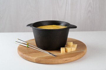 Fondue with tasty melted cheese and forks on white table