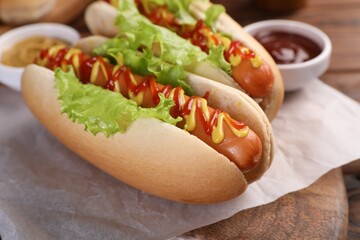 Tasty hot dogs with lettuce, ketchup and mustard on board, closeup