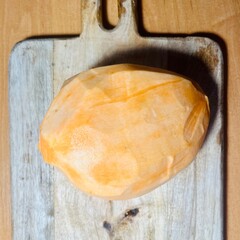 A whole peeled orange sweet potato lies on a wooden board. view from above. kitchen . vegan diet